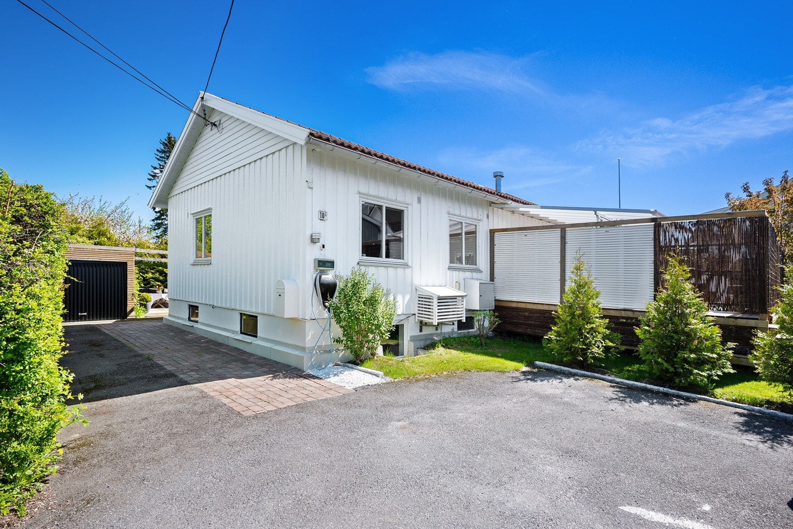 På fremsiden av tomten er det biloppstillingsplasser og ladepunkt til el-bil. Galleribilde