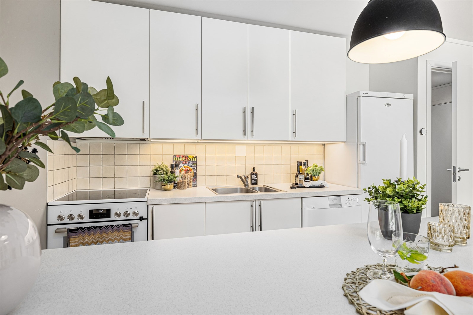 Innredningen er fra 2009, men ble oppgradert med nye kjøkkenfronter og benkeplate i 2018.
Kjøkkenet er utstyrt med frittstående komfyr, oppvaskmaskin, kjøleskap samt ventilator med kullfilter. Fryseren finner du i boden. Galleribilde