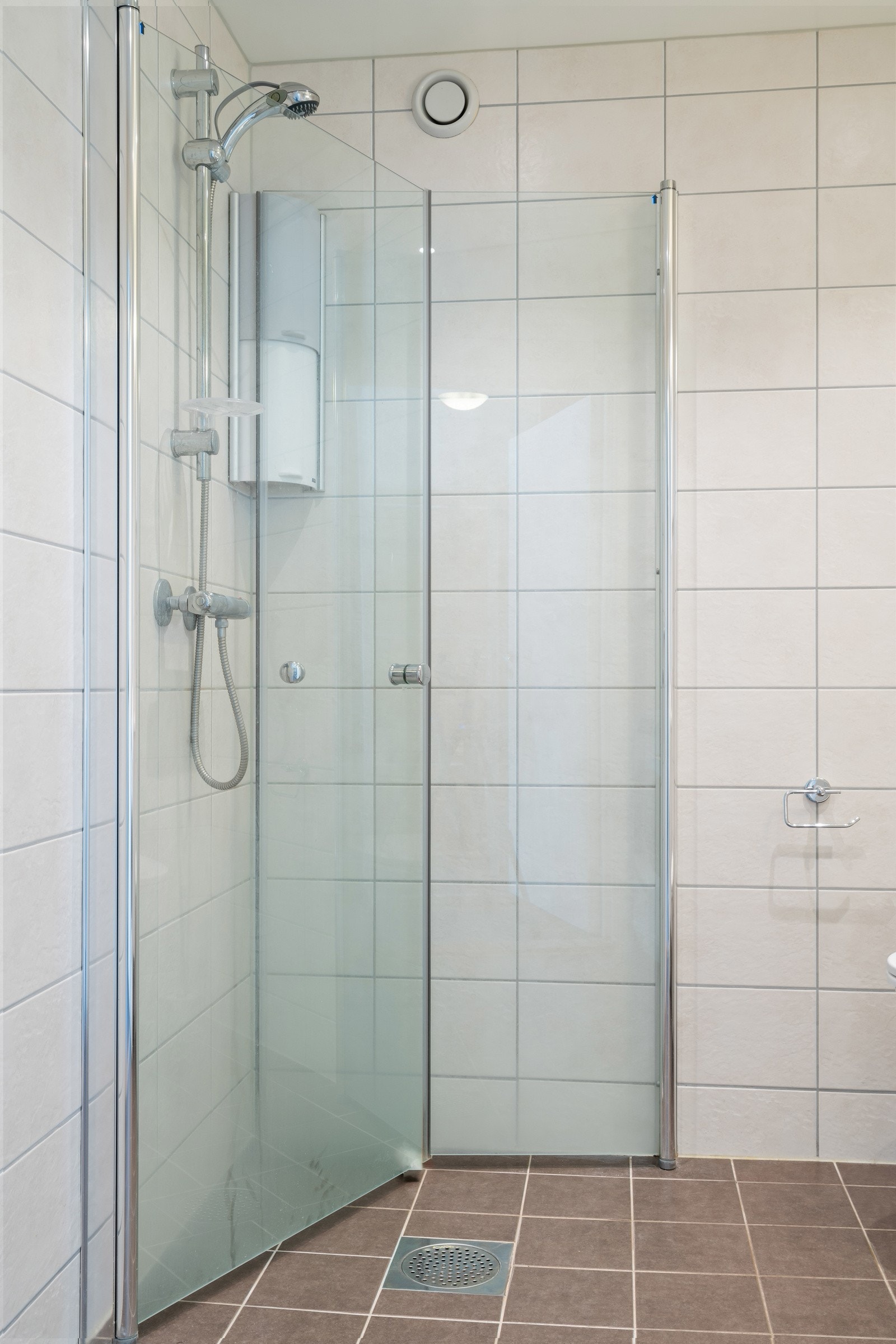 Dusjhjørne med innsvingbare glassvegger. Termostatstyrte elektriske varmekabler i gulvet gjør badet behagelig å bruke. Galleribilde