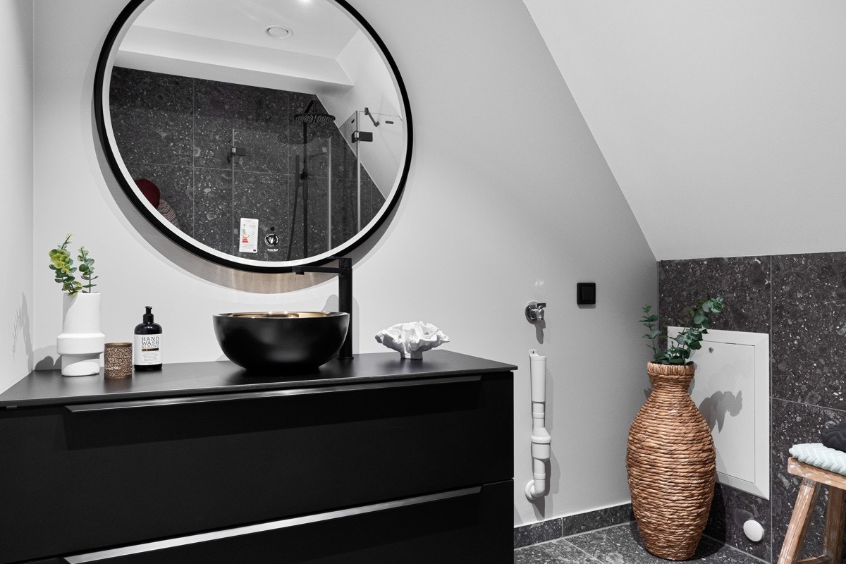 Badet har vegghengt toalett, åpent dusjhjørne med regnfallsdusj, og opplegg for oppvaskmaskin. Galleribilde