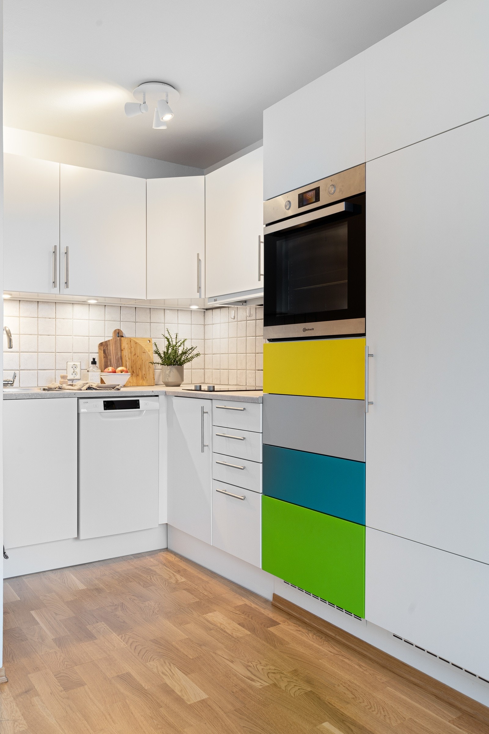 Kjøkkenet er innredet med lyse fronter og noen fargerike skuffer- her er det godt med lagringsplass Galleribilde