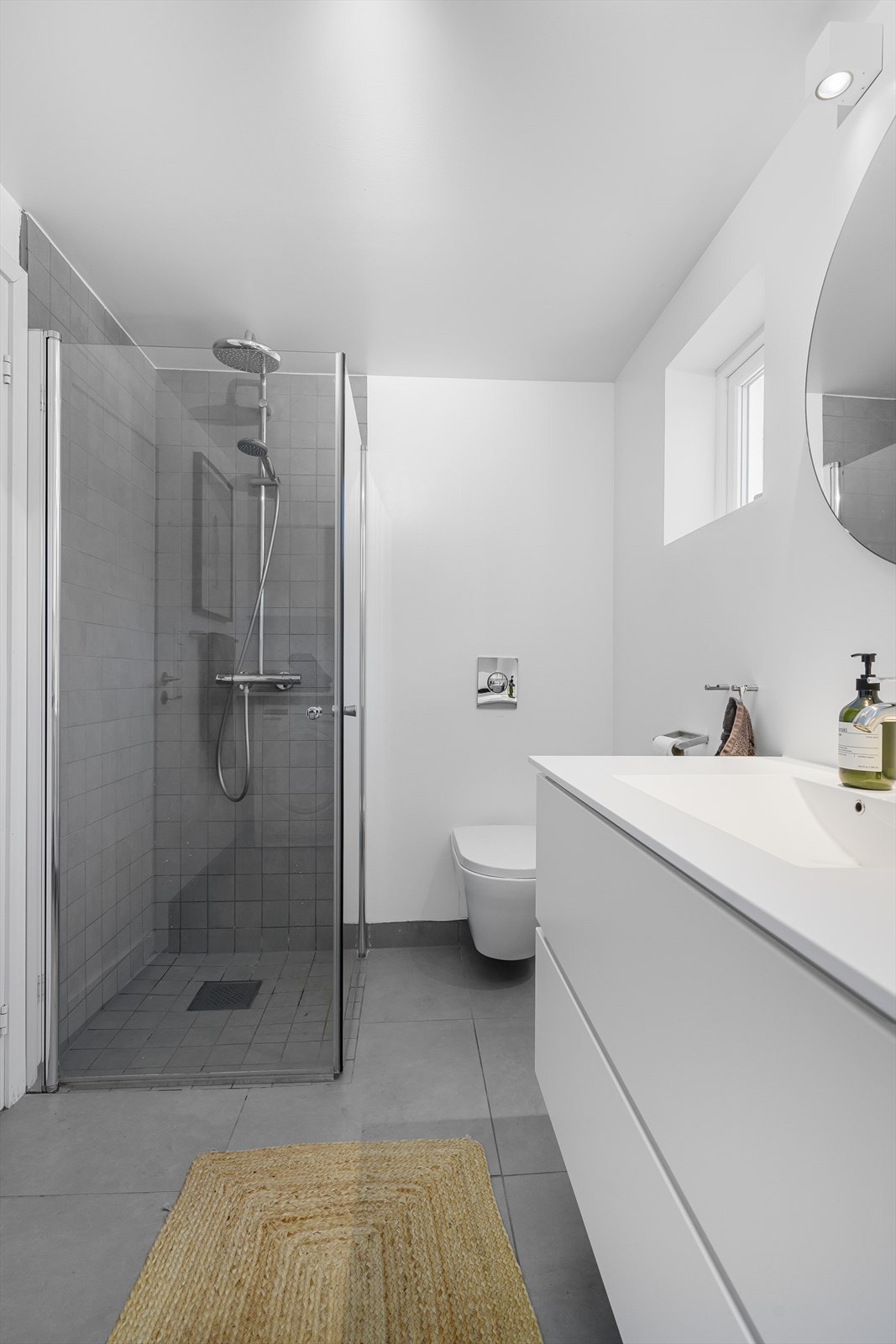 Badet innehar vegghengt toalett, dusjnisje med innfellbare dører og servant med skuffer. Galleribilde
