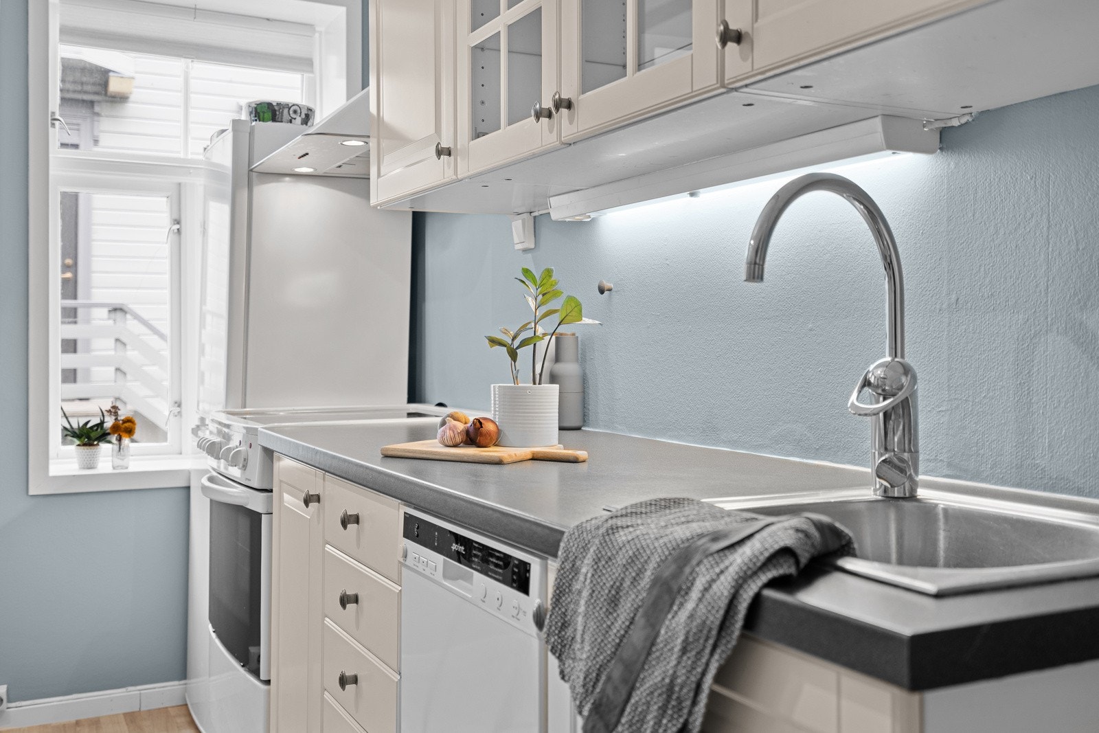 Praktisk kjøkken langs vegg med god skap- og benkeplass Galleribilde