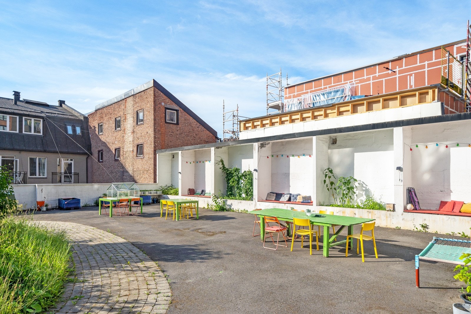 Fargerike bord i bakgården inviterer til sosial omgang, og i små nisjer med sitteputer kan man trekke seg tilbake om man ønsker det. Galleribilde