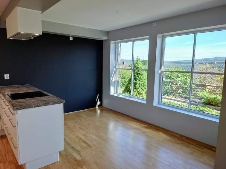 Plass til stort spisebord mellom kjøkken øy og vinduer. Galleribilde