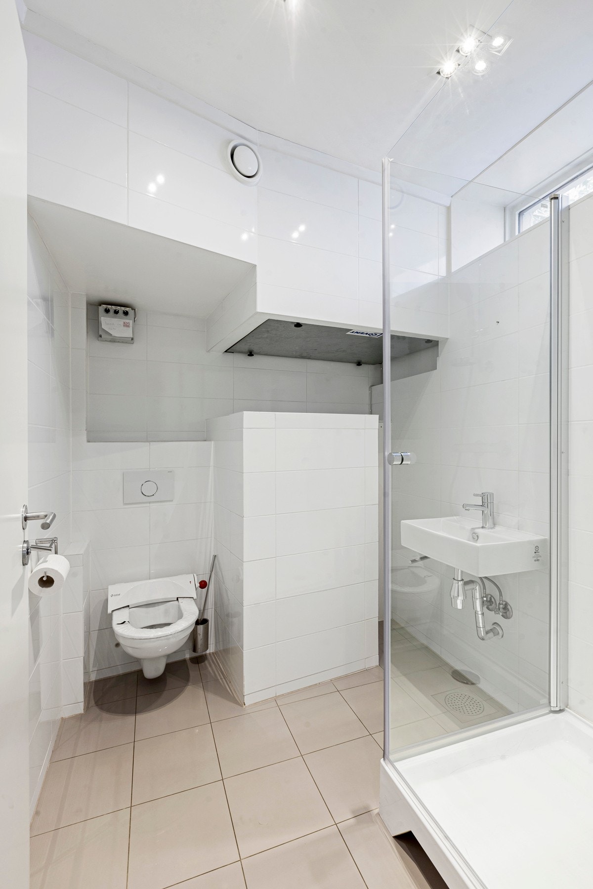 Bad i første etasje med gulvvarme, vegghengt wc, dusjkabinett og fliser i lyse farger. Galleribilde