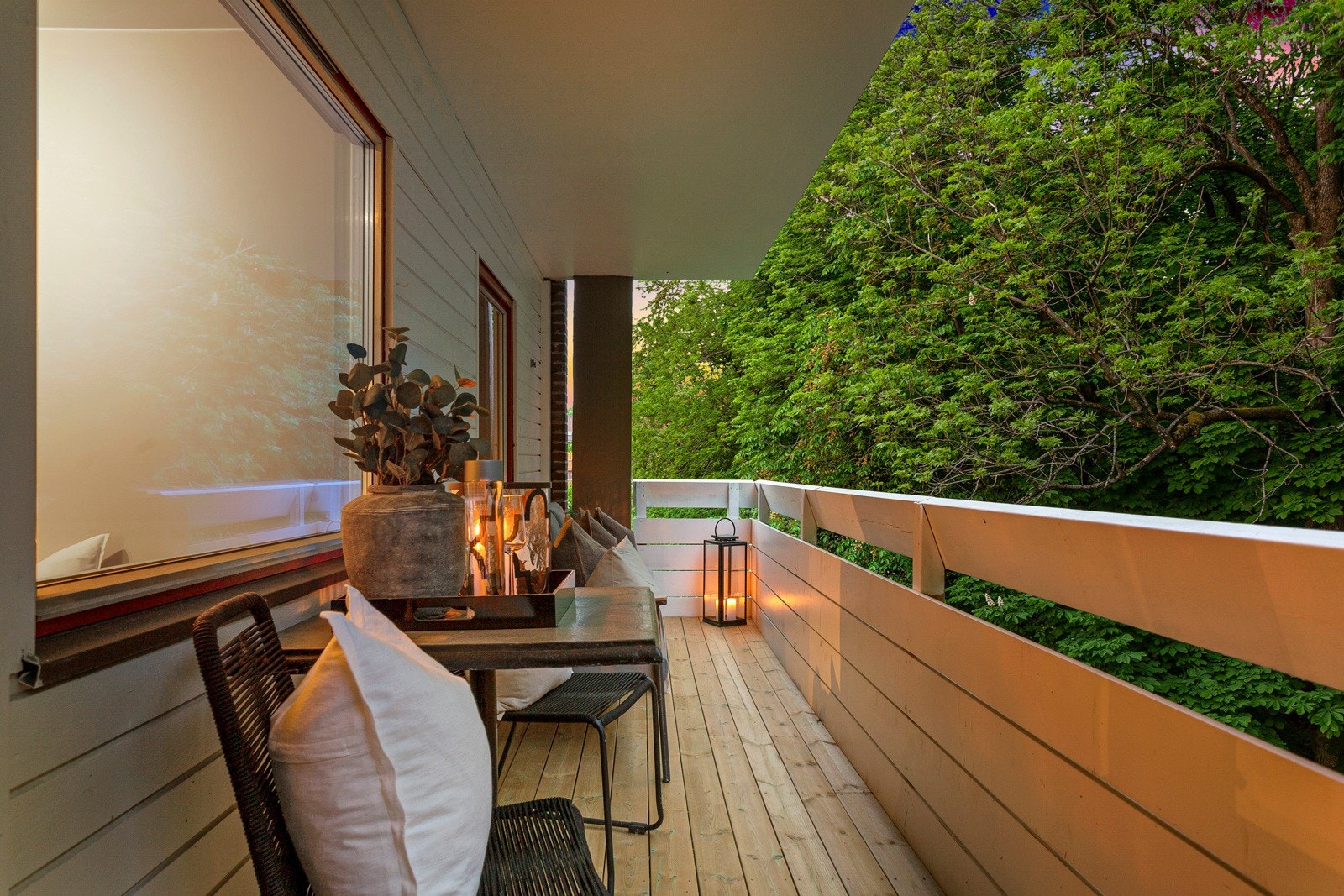 Balkongen byr på hyggelig utsyn mot et skogholt og har hvitmalt rekkverk i front Galleribilde