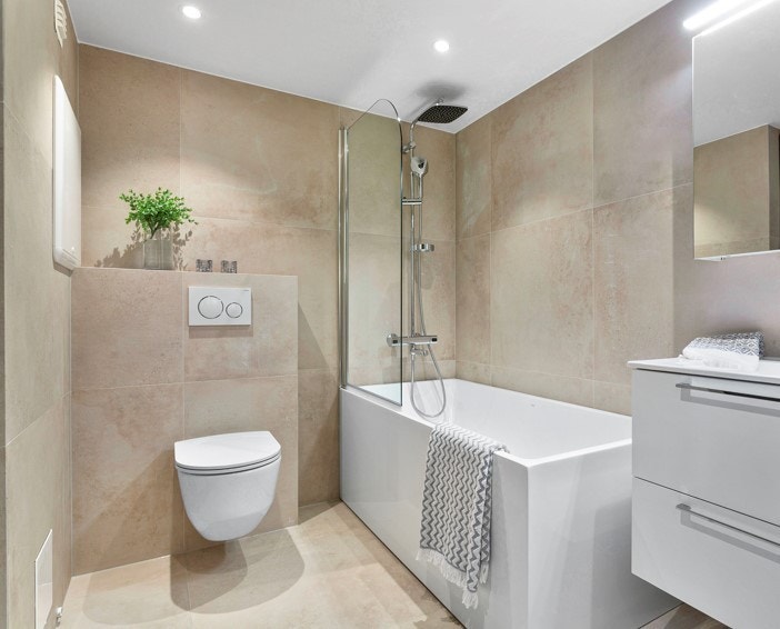 Det andre badet har adkomst fra entreen og har blant annet badekar, opplegg for vaskemaskin og tørketrommel, varmekabler og downlights Galleribilde