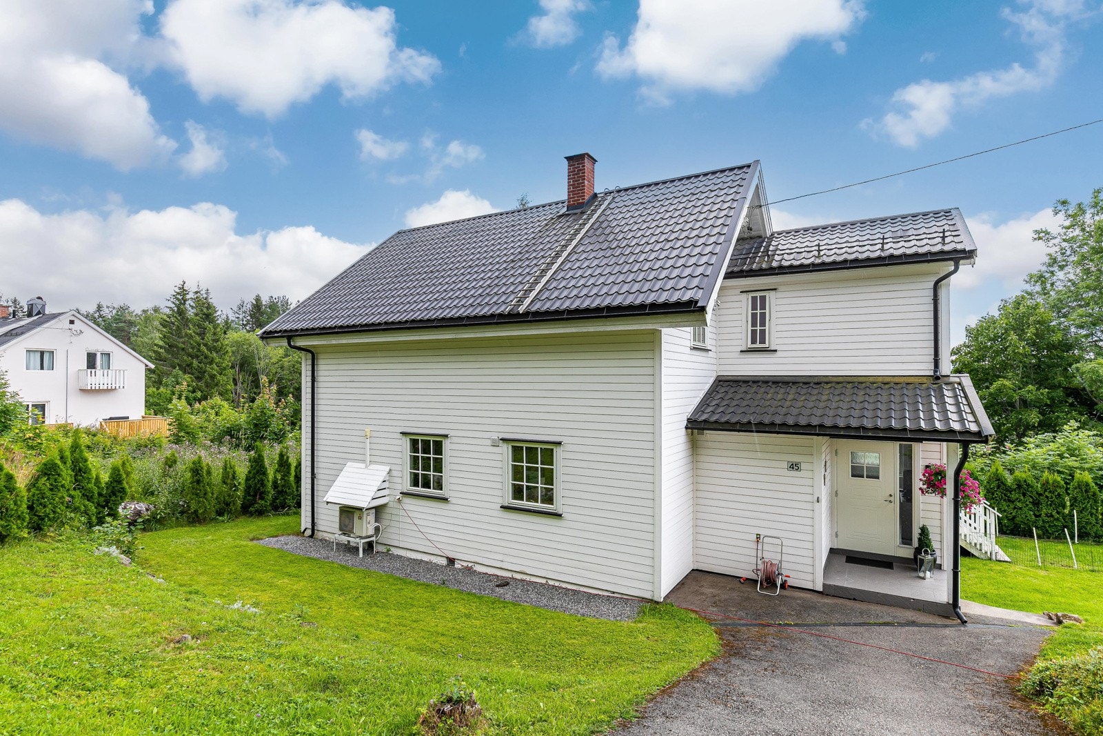 Tomten har asfaltert adkomst og er ellers opparbeidet med en fin hage rundt huset, som grenser til hekk og annen vegetasjon. Galleribilde