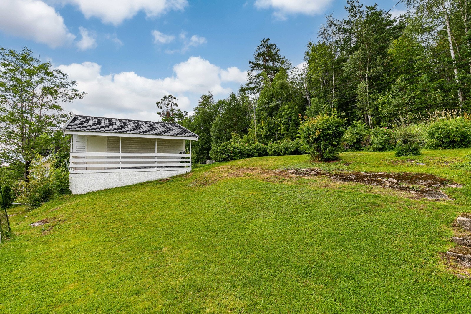 Hagen er avdelt med gjerde og har noe synlige fjell, samt et grusbelagt område inn mot husveggen. Galleribilde