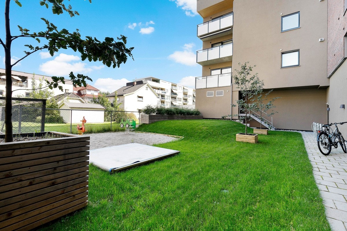 Fellesområdet er opparbeidet med plen, beplantning og lekeplass. Galleribilde