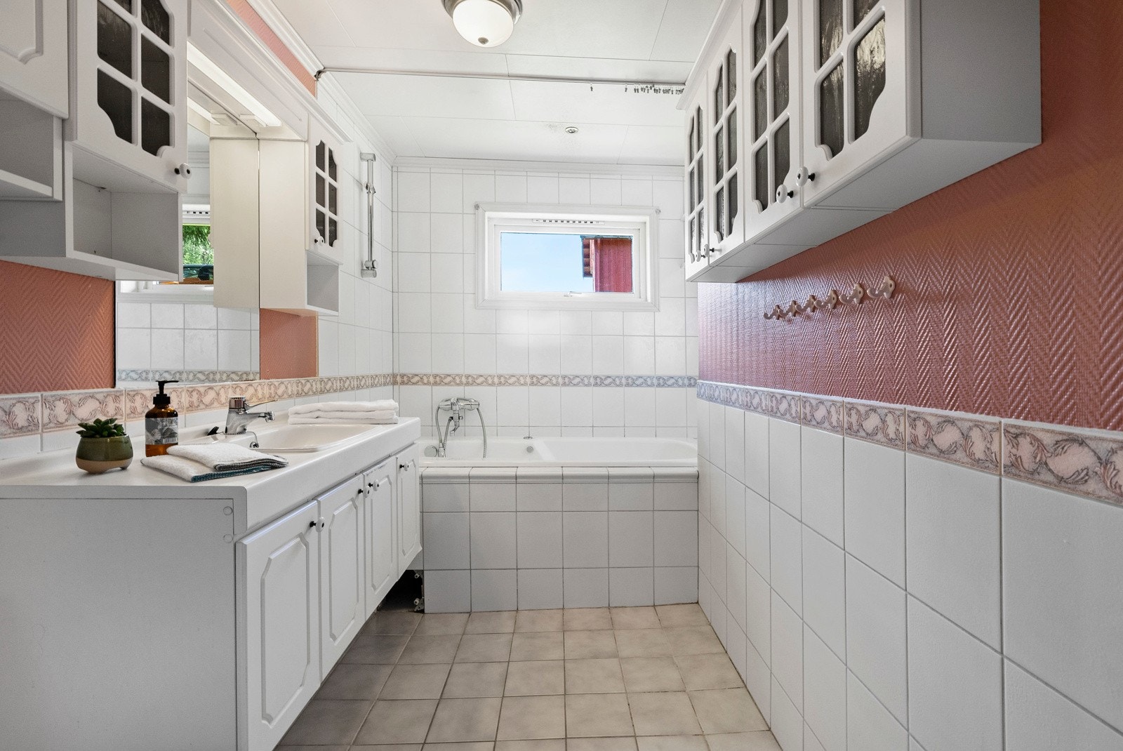 Fra gangen kommer du til badet. Delvis flislagt bad i lyse og behagelige farger. Rommet er innredet med servant med under- og overskap, speil, veggskap, innebygd badekar og frittstående toalett. Galleribilde