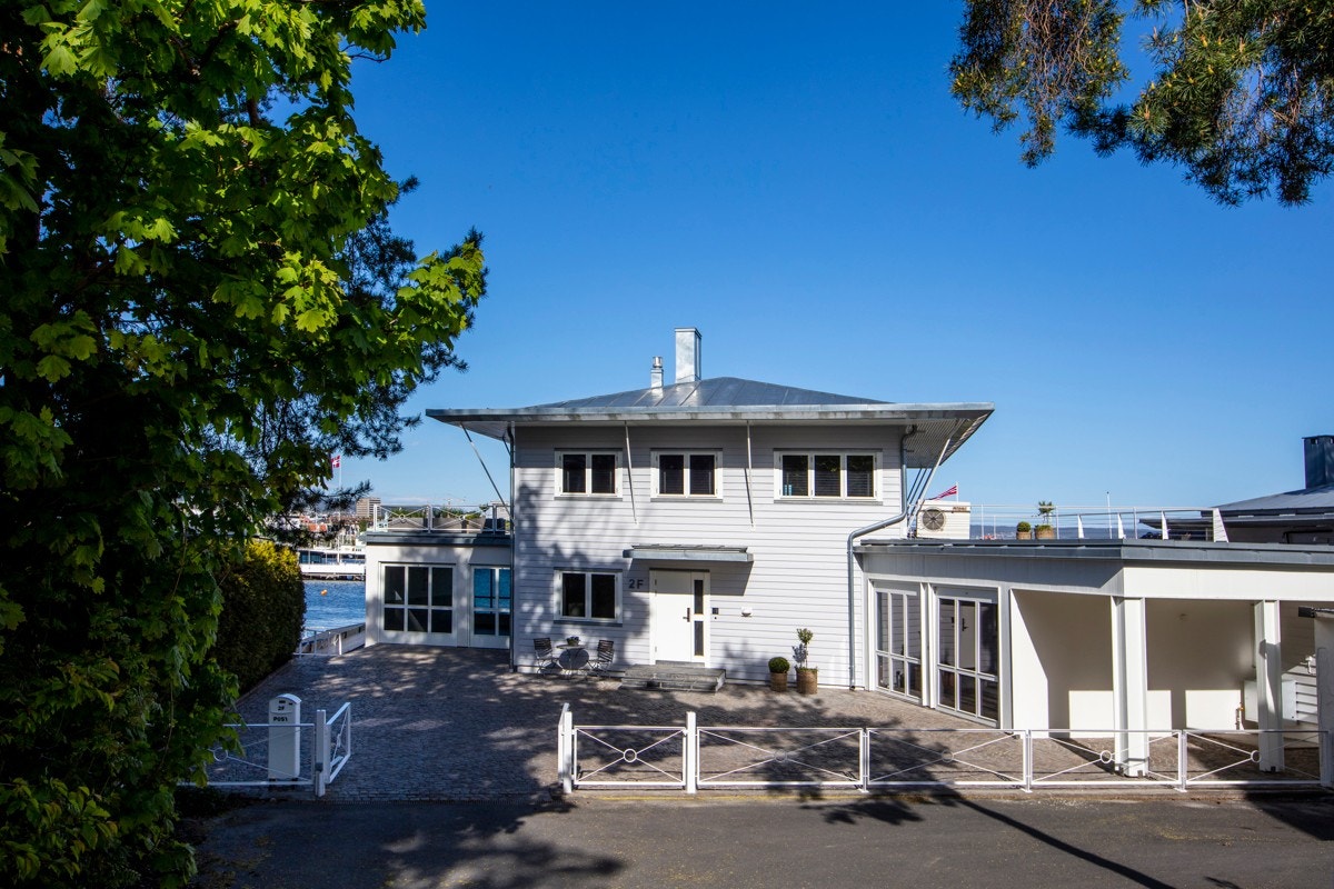 Gårdsplassen har brostein, og det er gjerde og port i malt metallkonstruksjon mot veien. Galleribilde