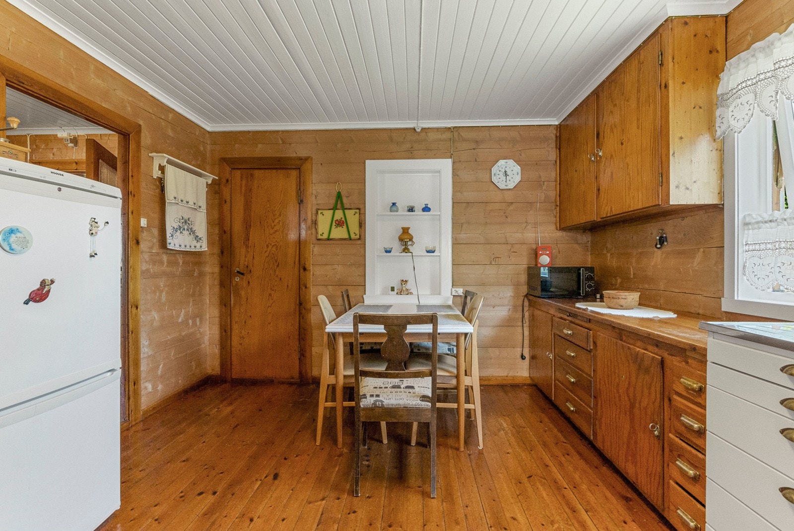 Kjøkkenet er innredet med over- og underskap, benkeplate i treverk, vask med to kummer og et større sidefelt i stål, komfyr og frittstående kjøleskap. Galleribilde