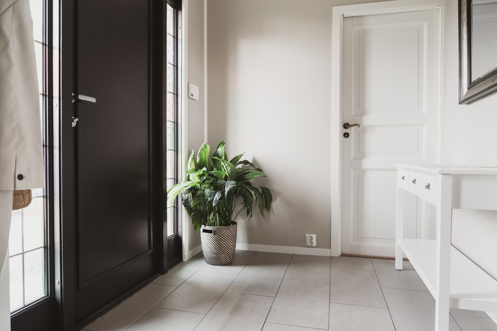 Vi tar oss inn i boligens entre på 4,5 kvm. Her møtes vi av slette overflater, malt i en lys og innbydende farge som kombineres med et moderne fliselagt gulv. Galleribilde