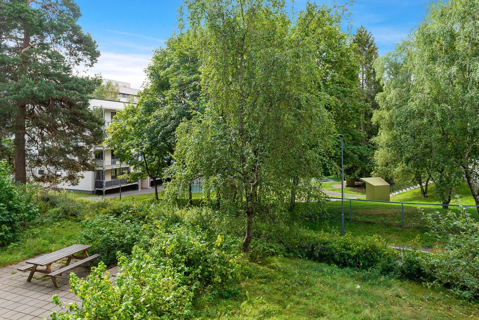 Utsyn fra balkong mot beplantet og pent fellesareal Galleribilde