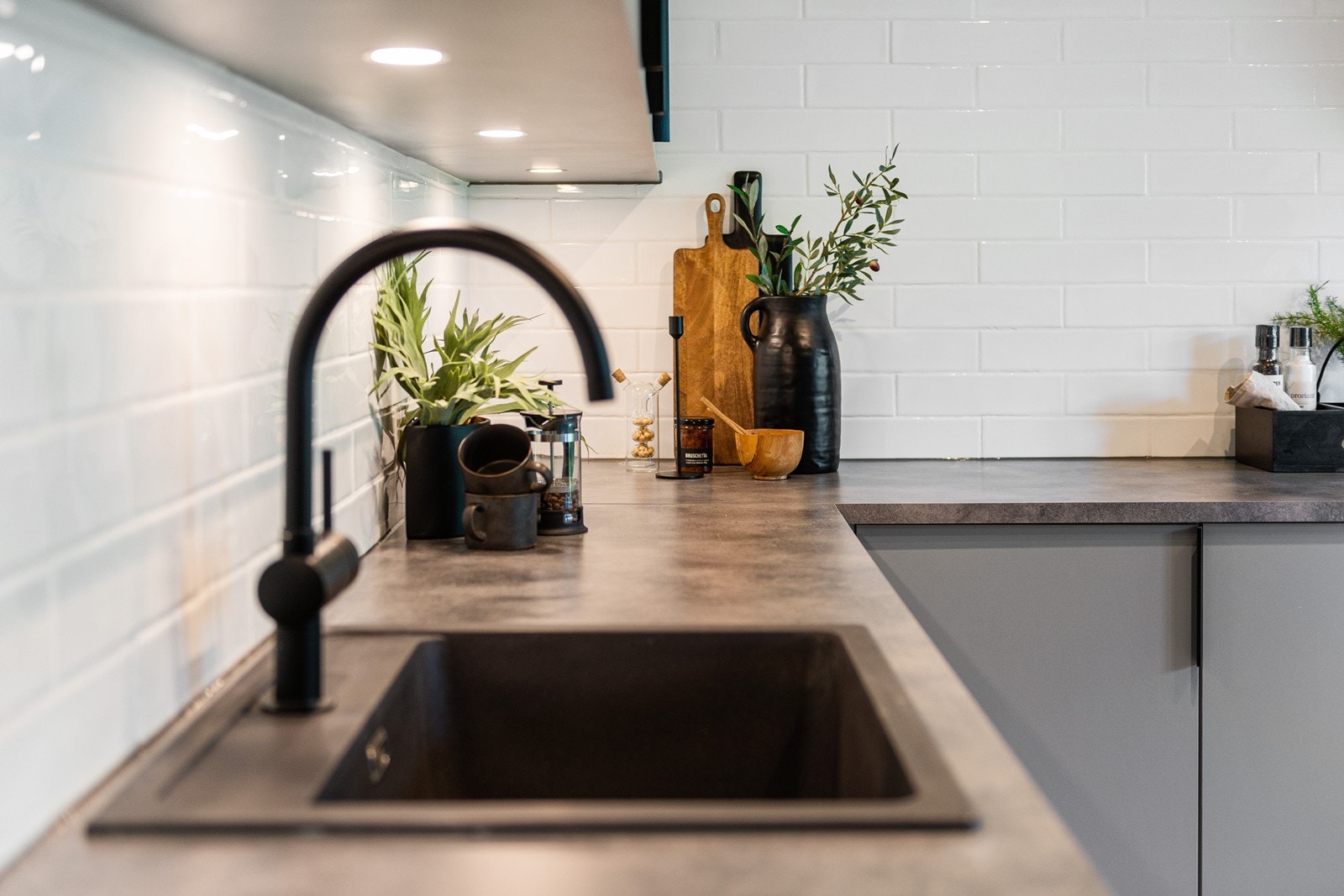 Laminat benkeplate, sort oppvaskkum, belysning under overskap og stilige fliser på vegg Galleribilde