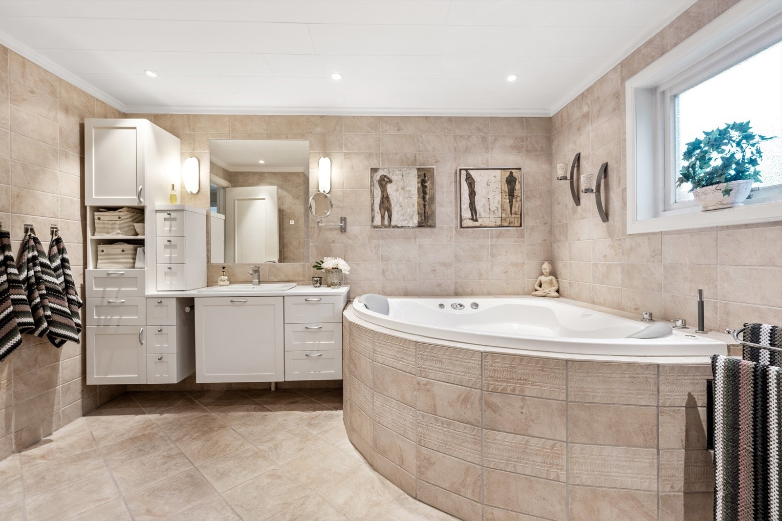 Badet er utstyrt med innmurt massasjekar, servantseksjon med nedfelt porselenvask, innmurt speil med lys - Galleribilde