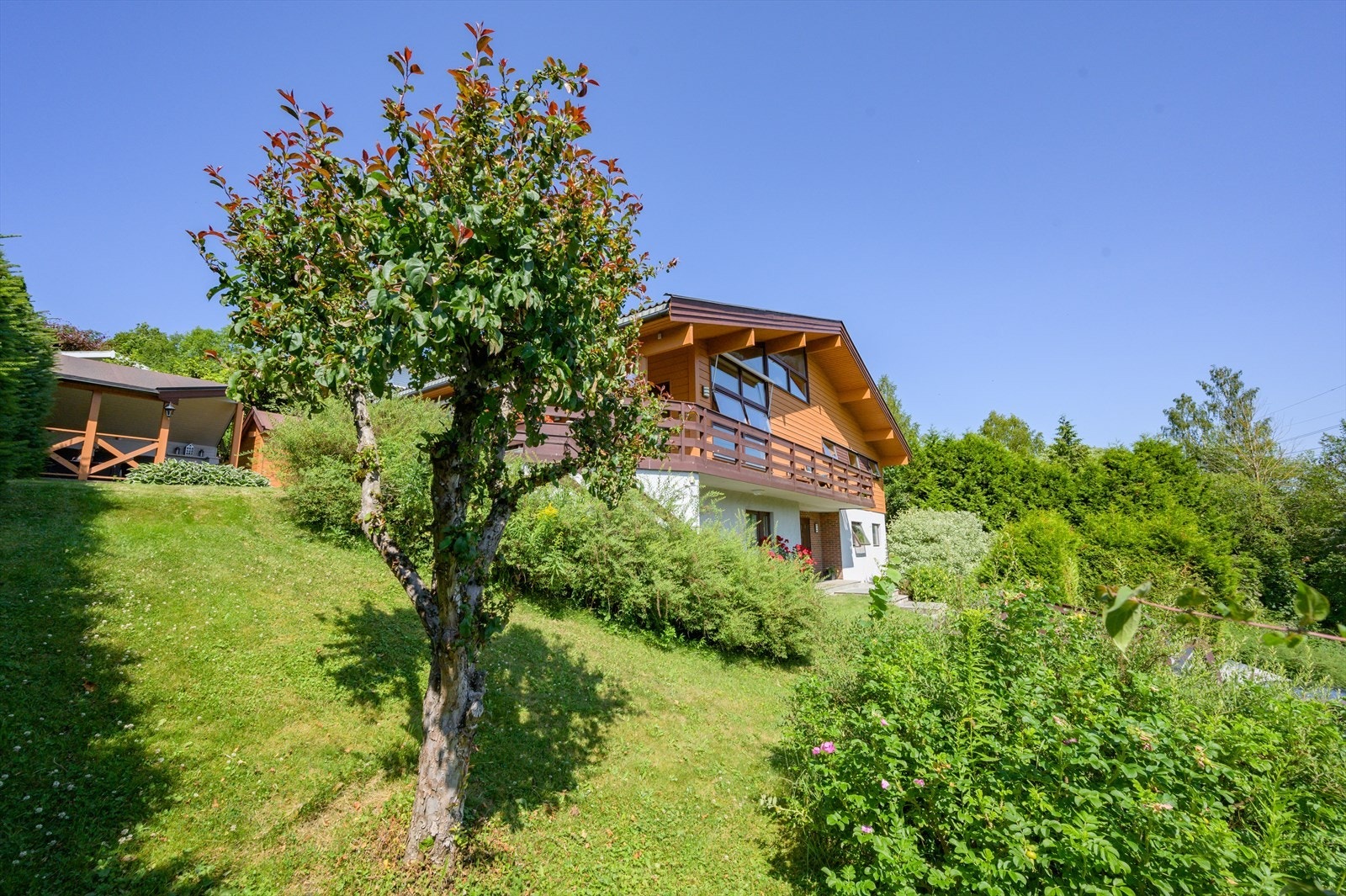 Tomten er pent opparbeidet med gressplen, beplanting og prydebusker Galleribilde