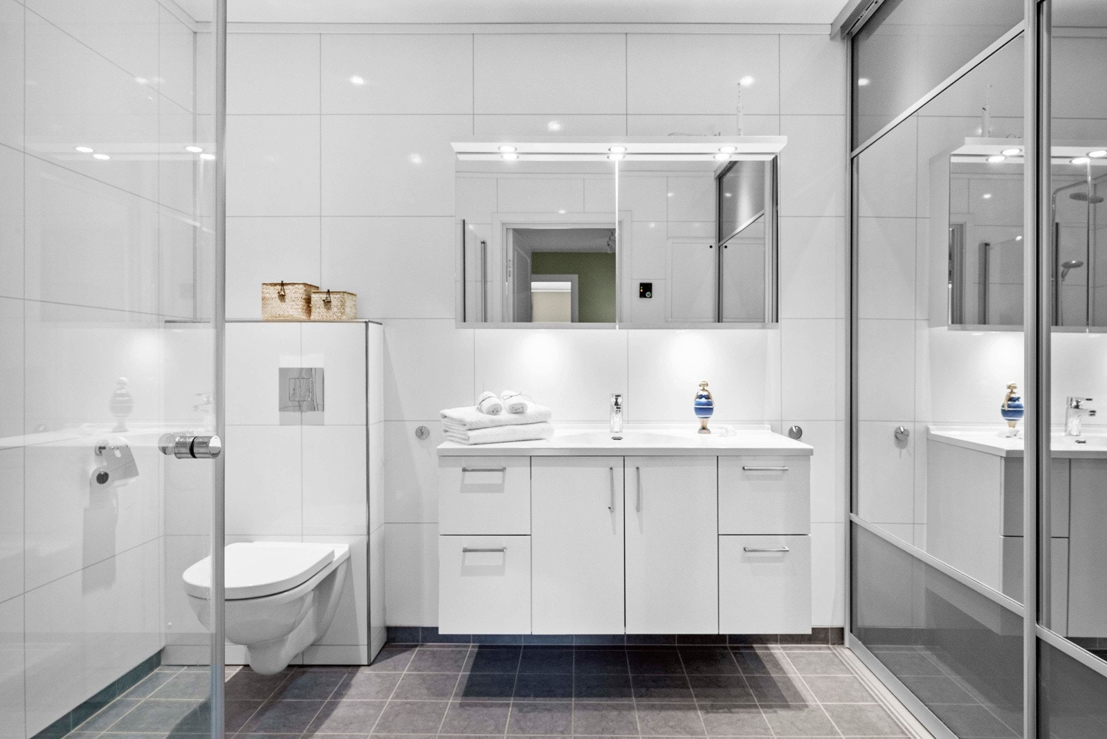Dette er badet i underetasjen, og fungerer som et kombinert bad og vaskerom. Bak skyvedørene finner du varmtvannstank, opplegg for vaskemaskin samt praktisk hylleløsning. Galleribilde