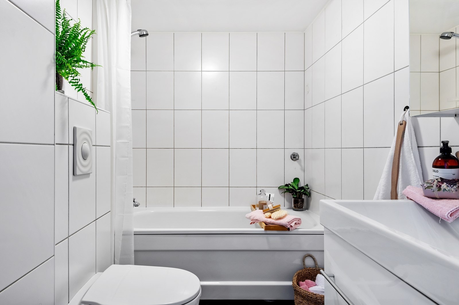 Badet har moderne baderomsinnredning med servantskap, speilskap, vegghengt toalett, samt badekar med dusj og forheng. Galleribilde
