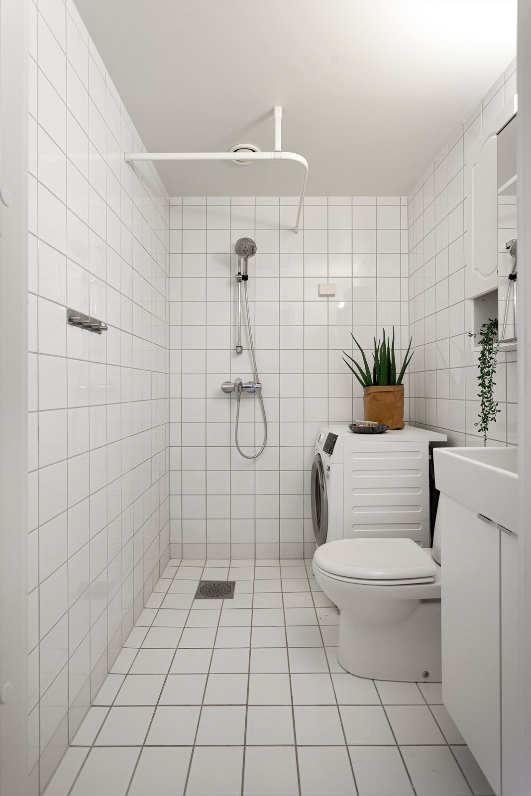 Badet inneholder dusj, klosett, servant med skapinnredning, speilskap og plass for vaskemaskin Galleribilde