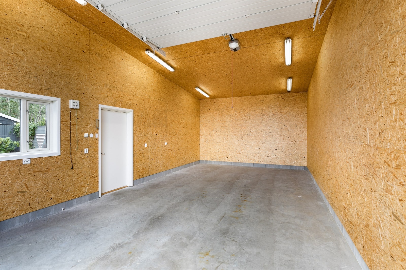 Garasjen har hele 4 meter innvendig høyde og plass til båtopplag, bobil eller løftebukk. Galleribilde