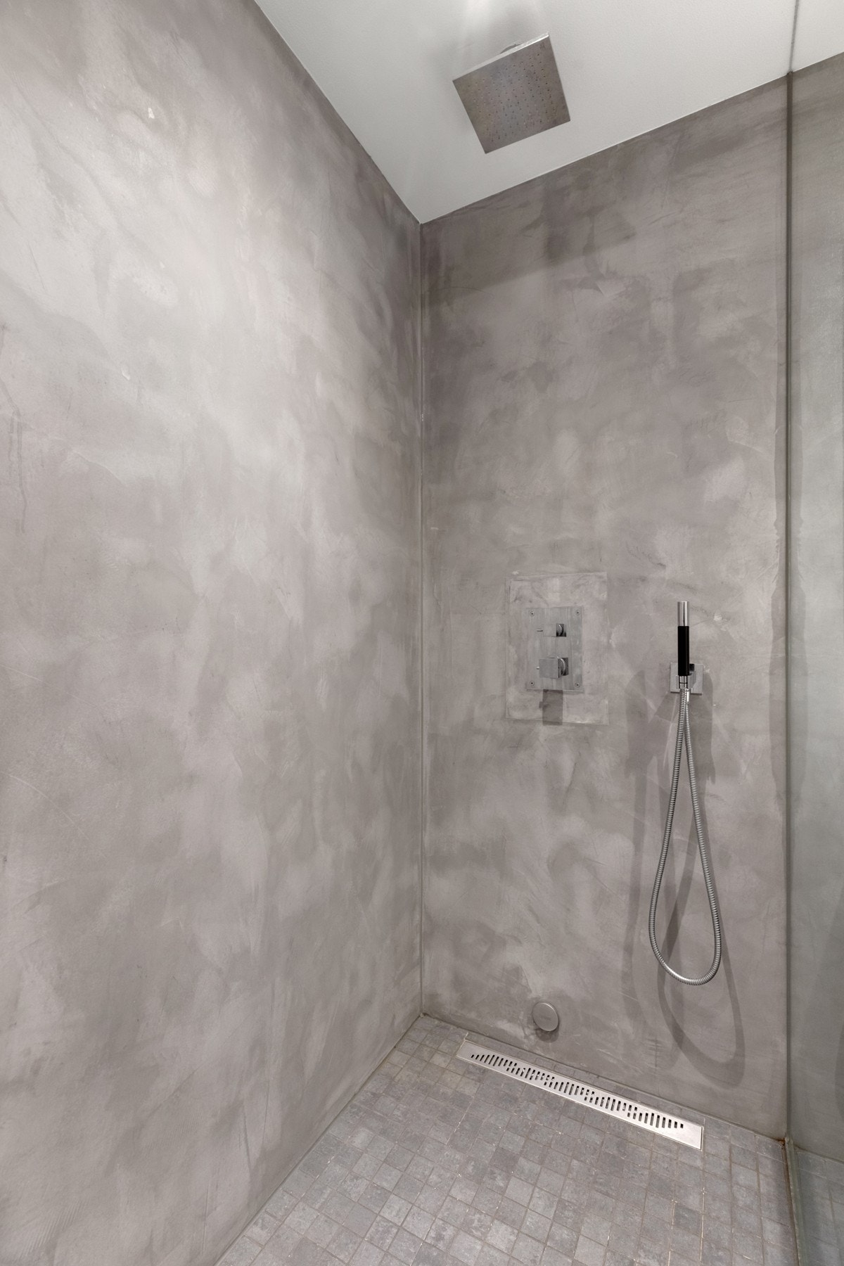 Dusjhjørne med mosaikkflis på gulv, designsluk og fast dusjvegg. Innebygget blandebatteri med hånddusj og takdusj i himling. Galleribilde