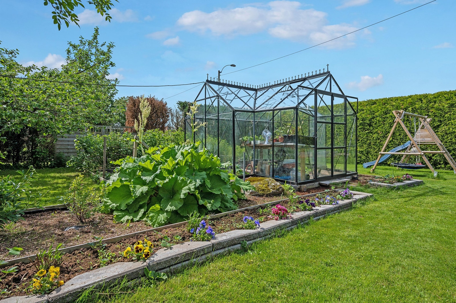 Drivhus og hage med bla. jordbær, rabarbra, moreller og epler samt bringebær, bjørnebær, rips, solbær og stikkelsbær Galleribilde