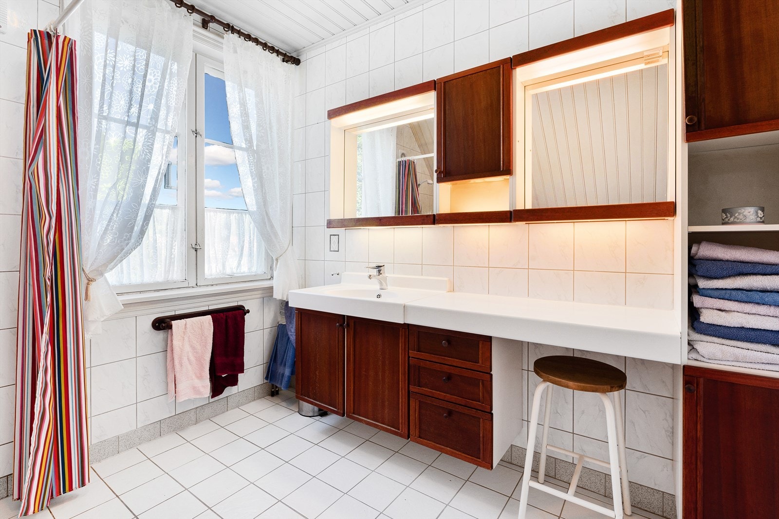 Helfliset bad med badekar, dusj og servant med skapinnredning. Galleribilde