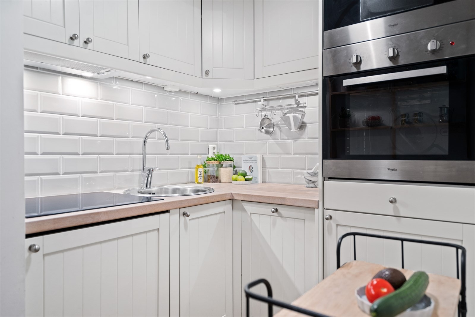 Kjøkkenet er lyst og moderne med fliser over benk og integrerte hvitevarer. Galleribilde