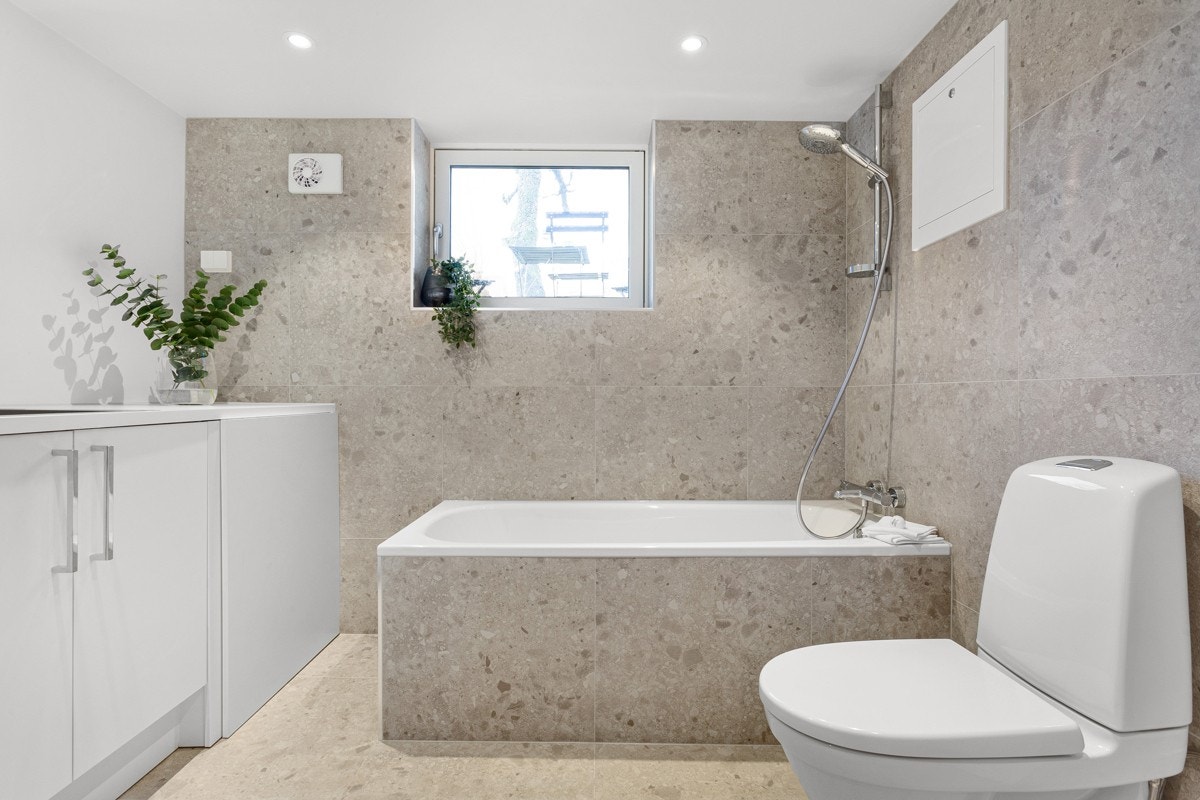 Badet i kjelleren ble pusset opp i 2021. Badet er innredet med store, flotte fliser på gulv og vegg samt innfliset badekar, noe som gir en følelse av hverdagsluksus. Rommet har et stort vindu som slipper inn godt med dagslys. Galleribilde