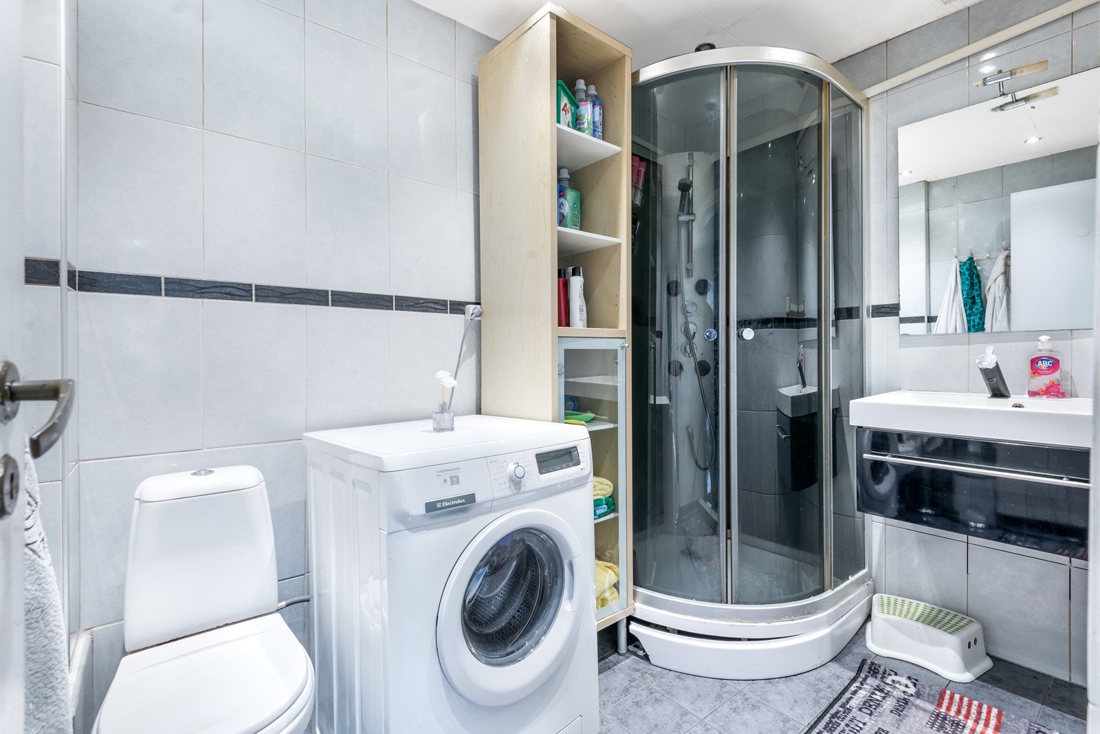 Flislagt bad med servantinnredning, dusjkabinett og gulvstående toalett Galleribilde