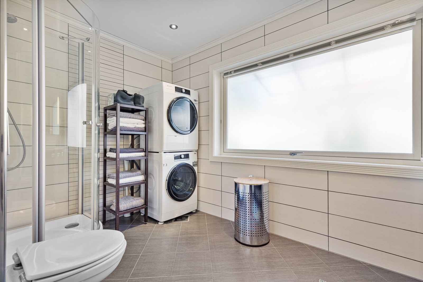 Badet inneholder vegghengt klosett, dusjkabinett, dobbel servant med innredning og opplegg for vaskemaskin/tørketrommel. Galleribilde