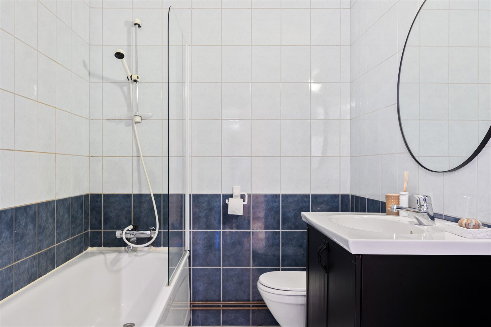 Innredningen består av mørke profilerte fronter og heldekkende servant, badekar med original sarg og svingbar halvvegg, bade-/dusjbatteri med dusjutstyr og en gulvstående toalett. Galleribilde