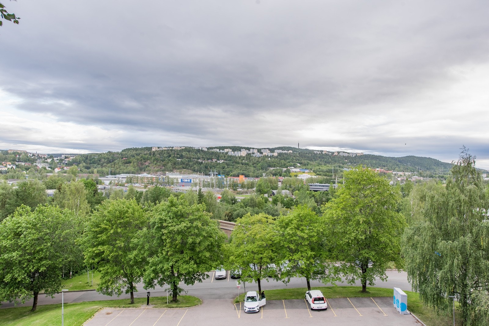 Utsikt fra balkongen over pen beplantning i brl. og helt over mot Røverkollen. Galleribilde