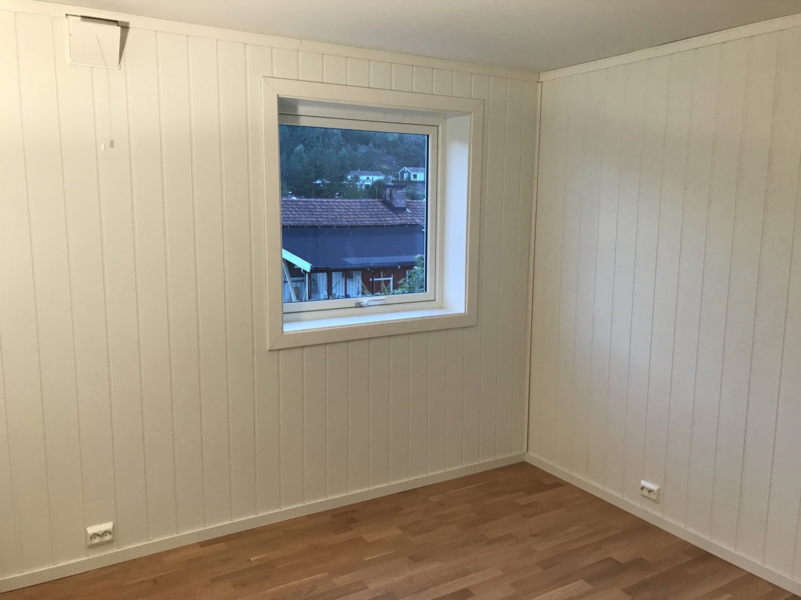 Del av stue med vindu mot hage. Parkett på gulv. God plass til sofa og tv-møbel. Galleribilde