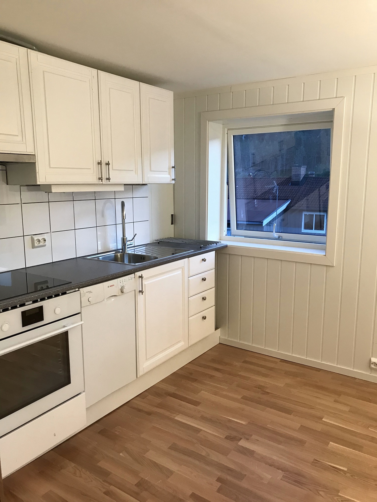 Lyst og praktisk kjøkken. Oppvaskmaskin, stekeovn og platetopp. Vindu mot hagen. Parkett på gulv. Galleribilde