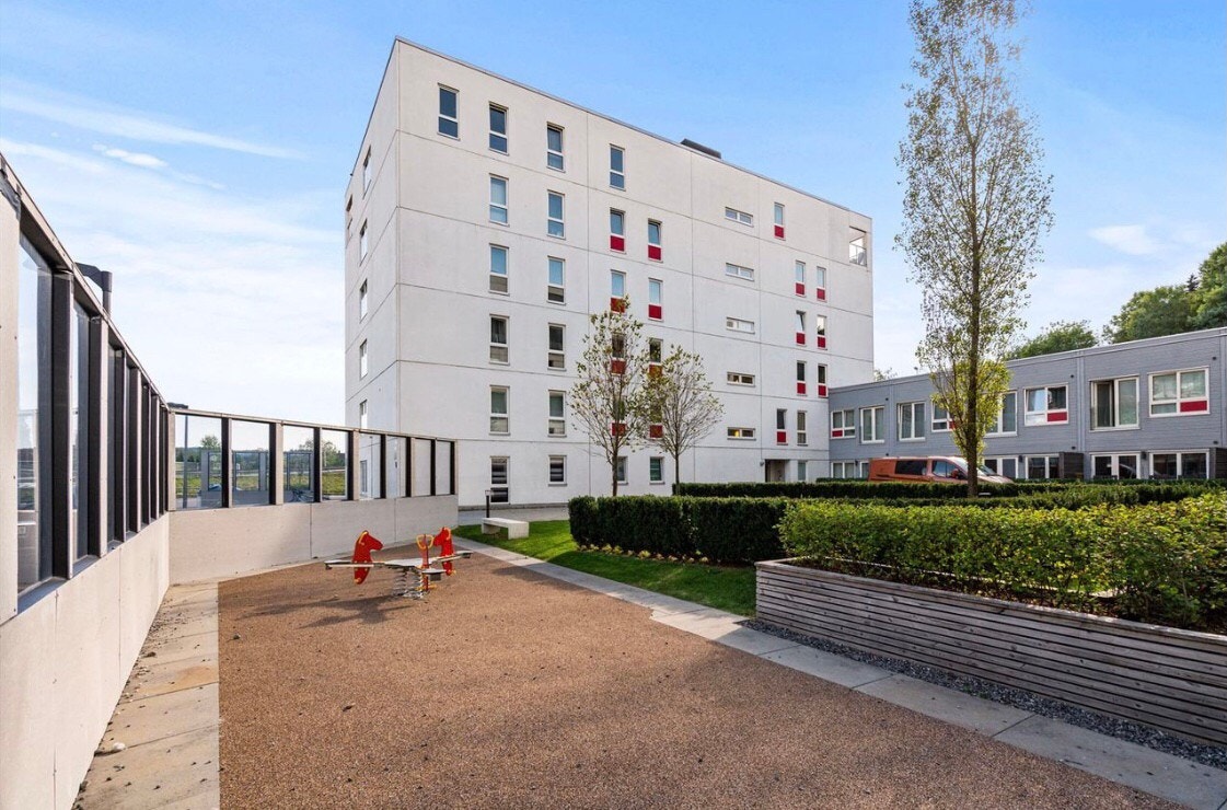 Pent opparbeidet fellesområde med bl.a. gressplen, beplantning, gangvei, lekeplasser og benker. Galleribilde