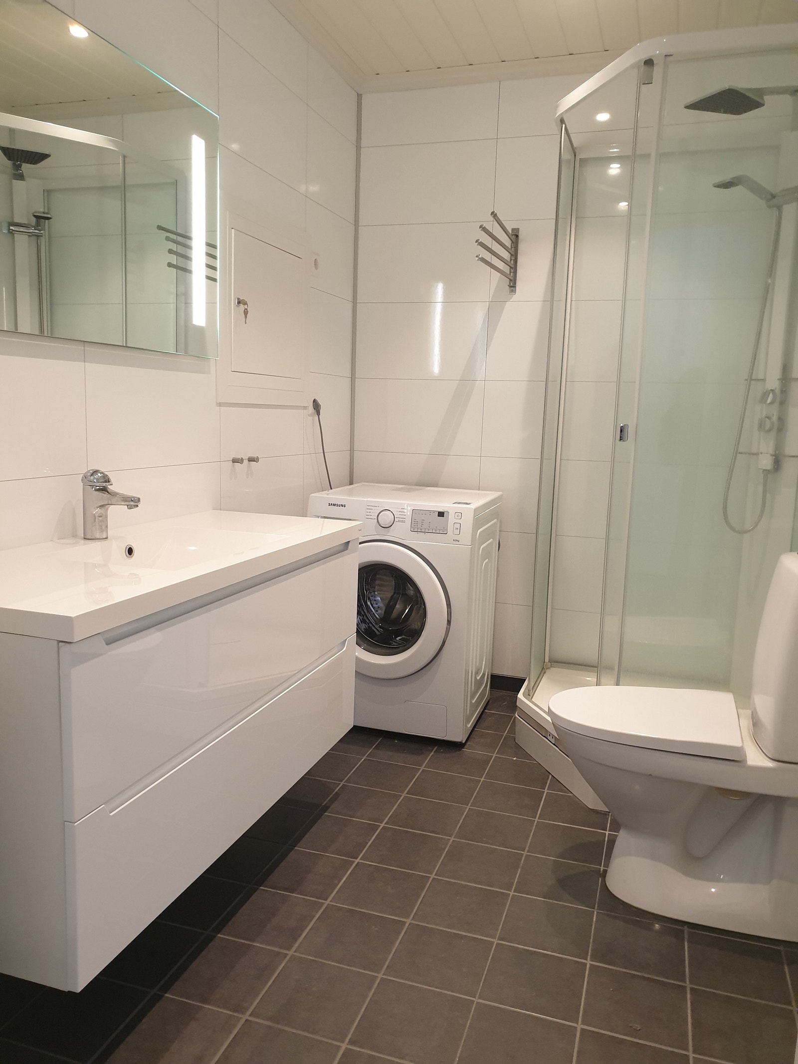 Bad med dusjkabinett, toalett og vaskemaskin Galleribilde