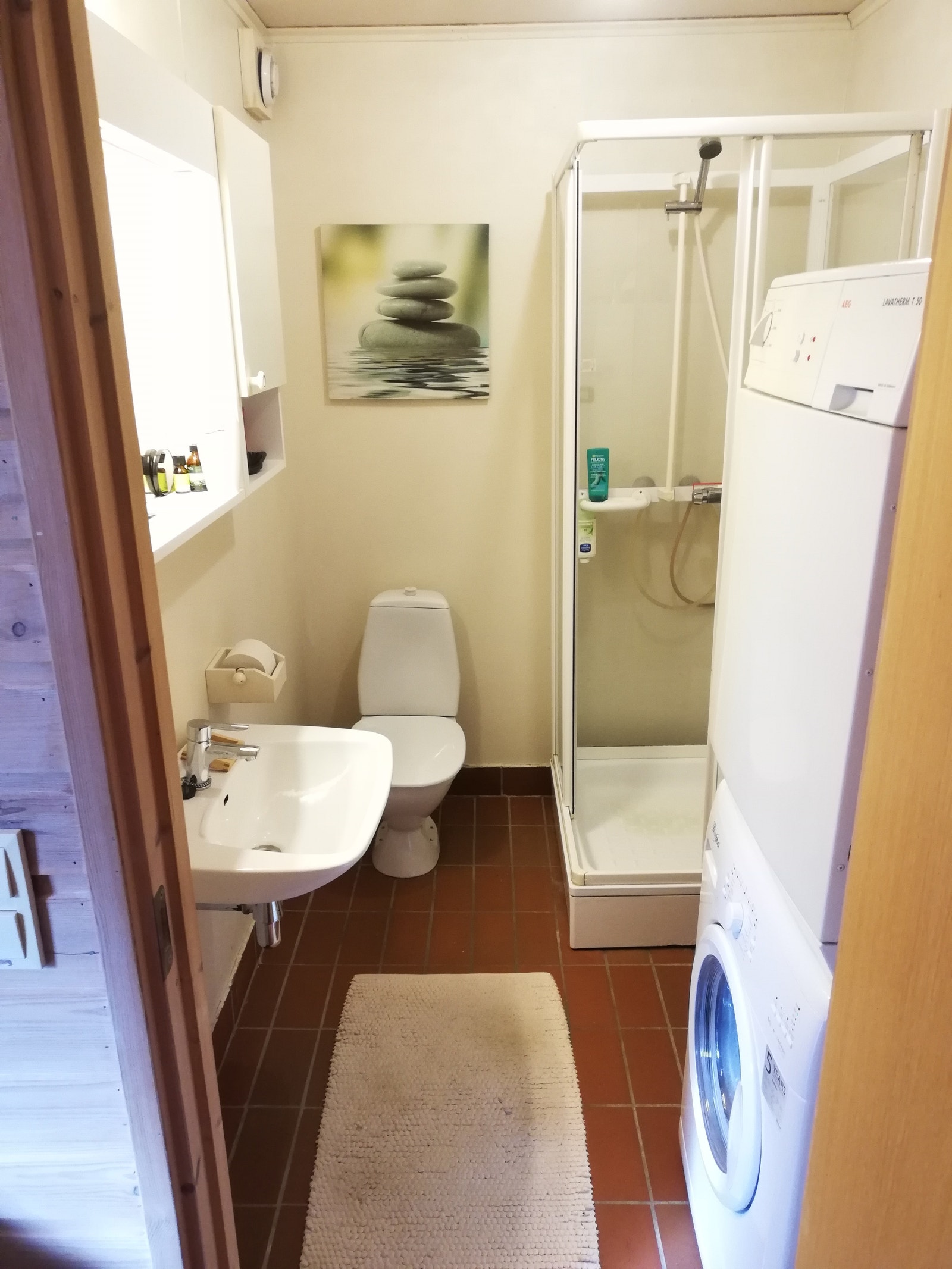 Lys-malt bad med toalett, dusj, vask, vaskemaskin og tørketrommel. Galleribilde