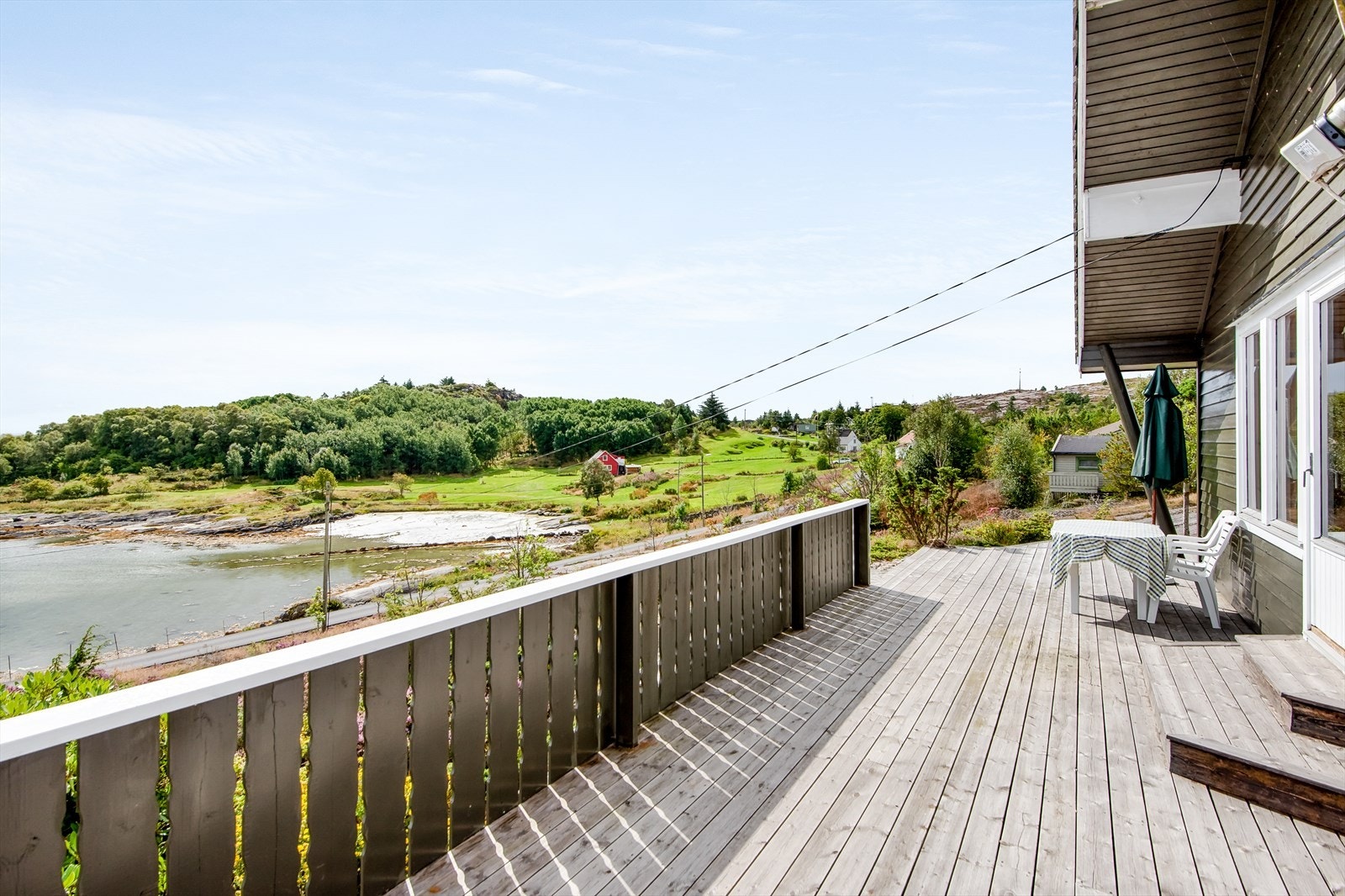 Solrik terrasse med utsikt mot sjø og båtfeste. Galleribilde
