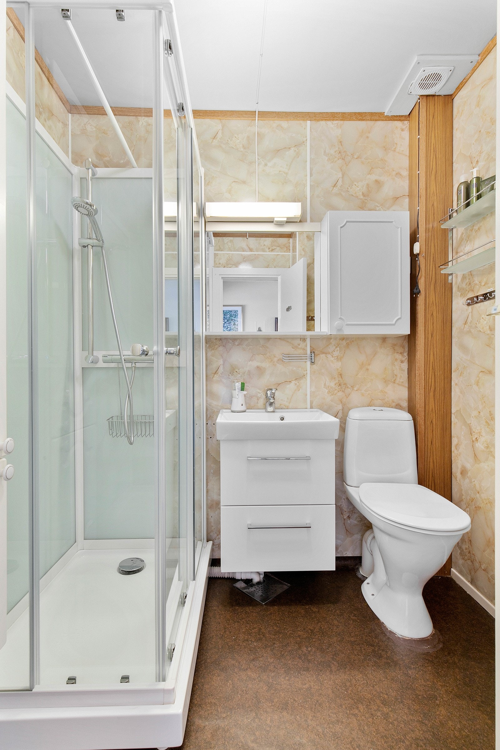 Badet ligger i første etasje, har et brunt gulvbelegg og vegger kledd i lyst våtromspanel. Galleribilde