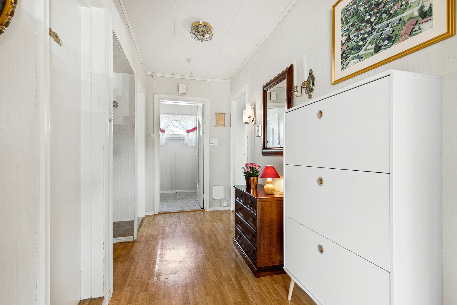 Entreen innenfor består av vindfang og en gang, begge med vinylbelegg på gulv og vegger holdt i lyse farger. Galleribilde