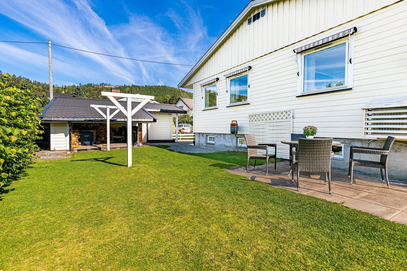 Fra terrassen er det trapp ned til hagen, og ved siden av trappen er det etablert en skjermet, hellebelagt uteplass. Galleribilde