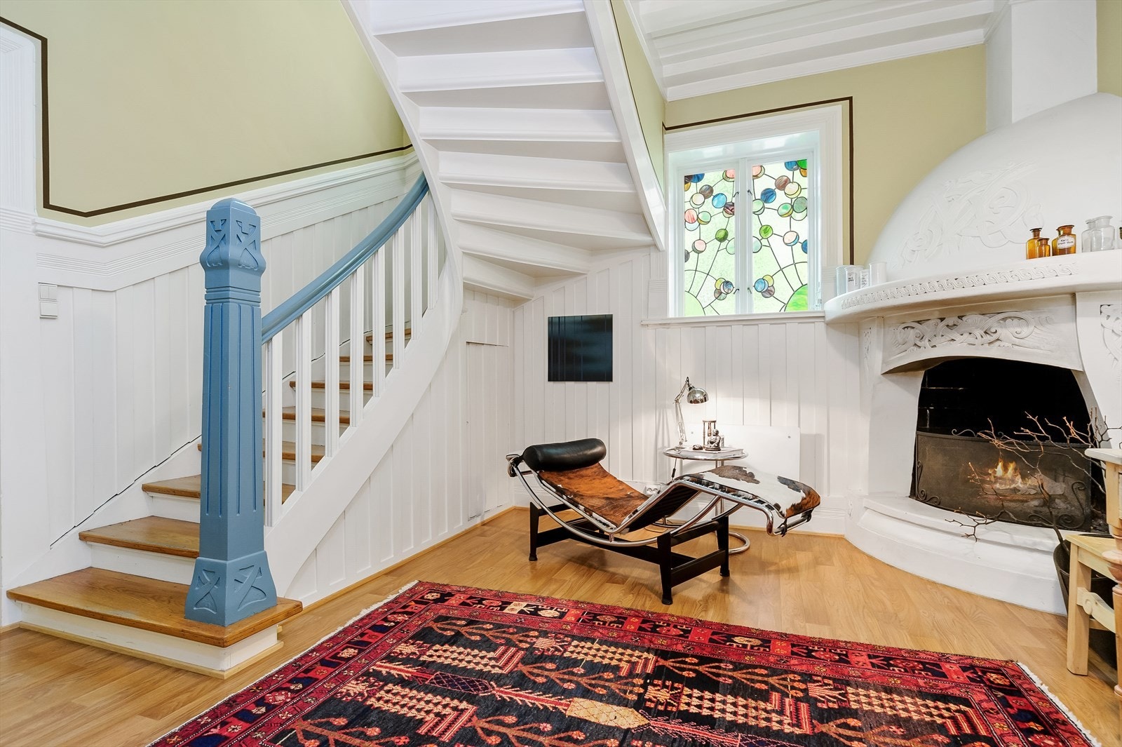 Den romslige hallen har peis med ornament i dragestil og et flott glassmaleri Galleribilde