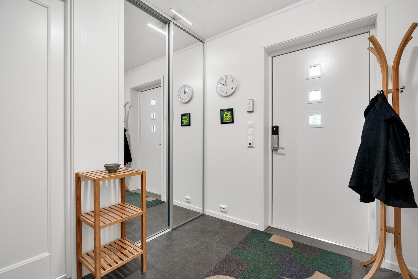 Flislagt inngangsparti og skyvedørsgarderobe med store speil. Varme i gulv.