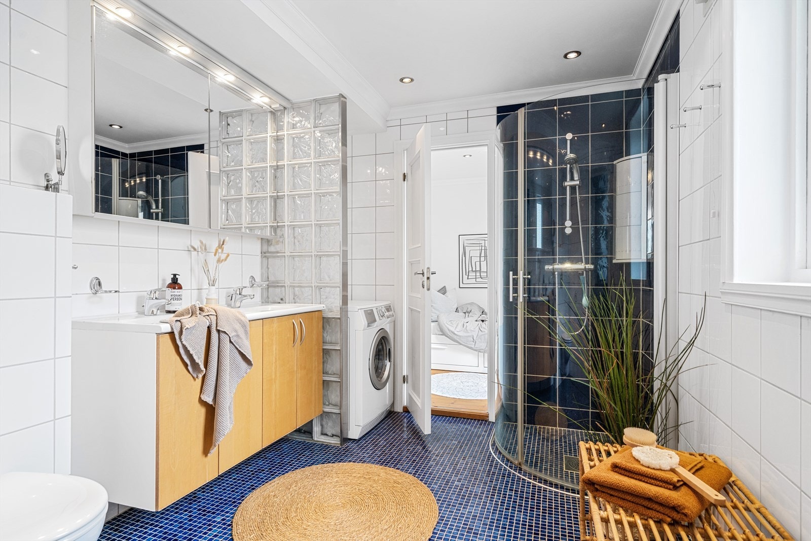 Nisje av glassbyggerstein for vaskemaskin og tørketrommel på badet. Ellers inneholder badet dusjhjørne med innsvingbare dusjvegger i glass og vegghengt toalett. Galleribilde