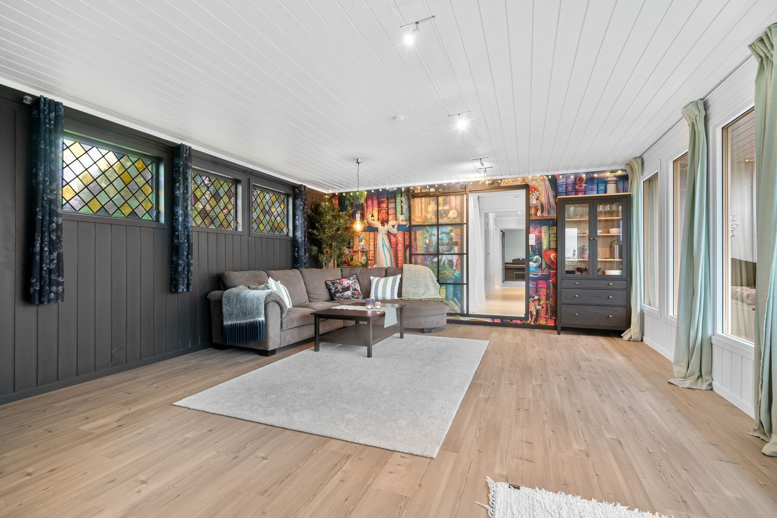 Stuen har laminat på gulv, malte flater, tapet og malt panel på vegger samt malt panelhimling. Galleribilde