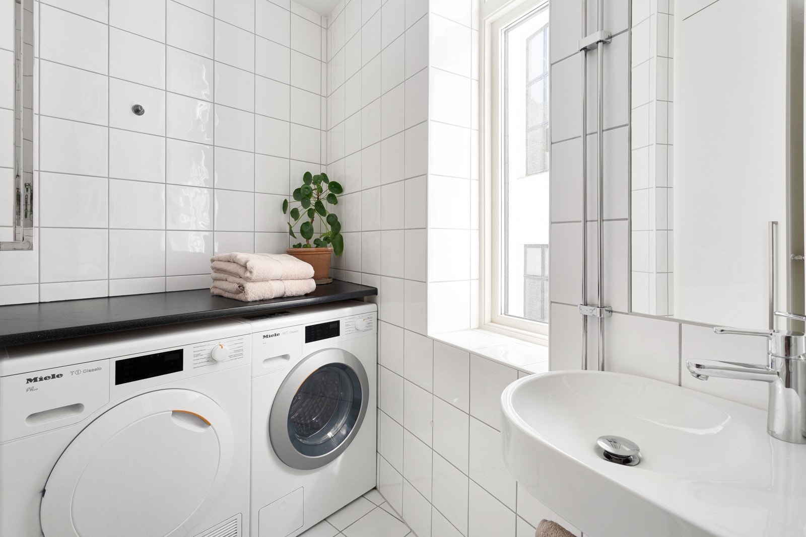 Lyst bad som ligger i praktisk tilknytning til entréen, utstyrt med opplegg for vaskemaskin og tørketrommel. Galleribilde